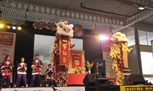 dragon dance performance on stage, two costumed dragons are standing upright with a red banner hanging from their mouths